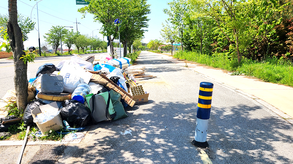 봉덕~신운가 도로 주변 마을 앞에 쓰레기가 쌓여 있다.